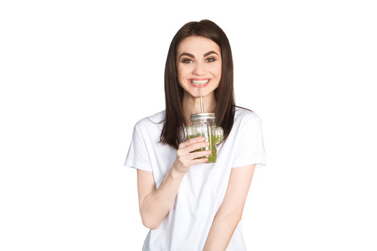 Smiling Young Woman Drinking Green Smoothie Juice On A White Background. Healthy Lifestyle.