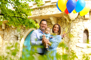 Young beautiful parents posing in park with their little baby boy