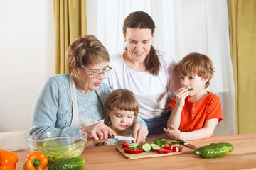 Obraz na płótnie Canvas Happy family mother, grandma and two little kids are preparing the vegetables in salad in the kitchen. Healthy Lifestyle food.