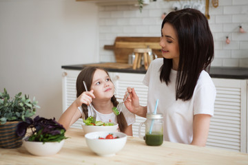 Obraz na płótnie Canvas Mother and daughter eat vegetables salad together in the kitchen. Healthy Lifestyle.