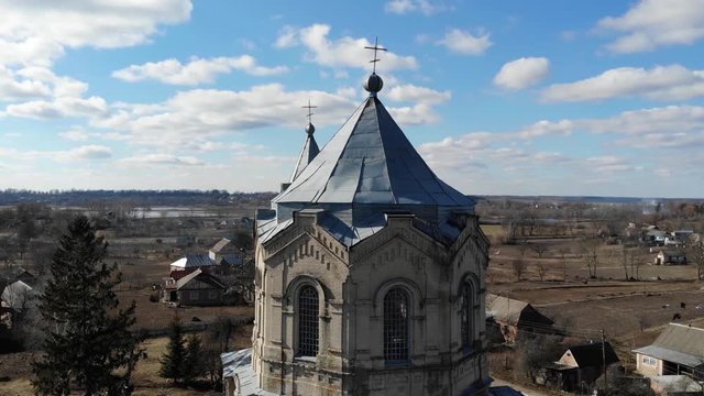 Aerial view of the old Catholic Church in Ukraine with pegeons near it. Top view from drone with beautiful landscape and blue sky