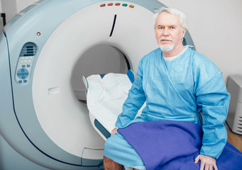 senior man sitting on scanner table. waiting for CT scan