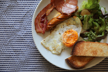 English breakfast fried egg bacon sausage bread and salad