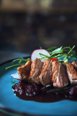 Duck confit with salad , baked apple and raspberry sauce served on wooden table