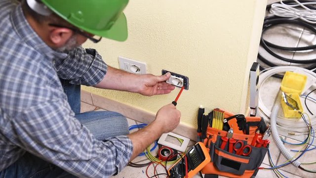 Electrician technician worker with the screwdriver engaged to repair an electric socket in a residential electrical system. Construction industry. Building. Footage. 