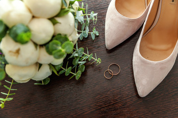 Beautiful wedding bouquet of flowers rings bridal shoes on wooden background. Declaration of love, spring. Wedding card, Valentine's Day greeting. Wedding rings. Wedding day details
