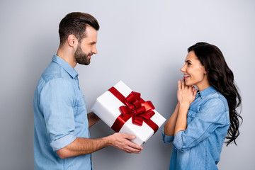 Its for me Profile side view photo of two youngsters spouses giving giftbox for 8-march 14-vebruary anniversary dressed in blue denim jackets isolated on silver backgorund