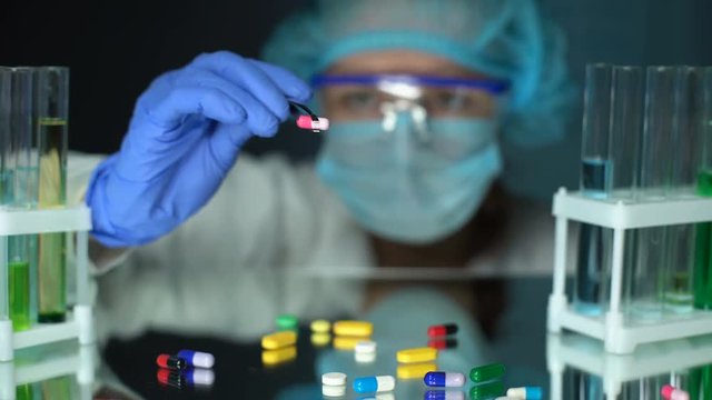 Lab assistant analyzing medication capsules, counterfeit pharmaceuticals, study