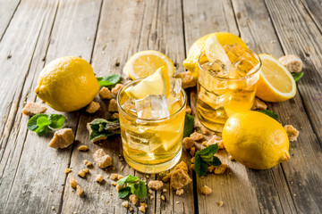 Lemonade or iced summer tea, with fresh lemon slices, sugar and mint leaf, rustic wooden table, copy space