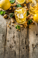 Lemonade or iced summer tea, with fresh lemon slices, sugar and mint leaf, rustic wooden table, copy space