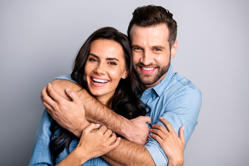Fototapeta premium Close up photo of handsome casual joyful cute spouses cuddling bonding placing arms around neck sharing rejoice dressed in blue denim clothing isolated on argent background