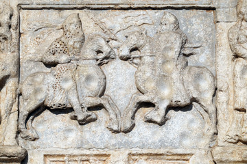 Knights fight horseback with lance and shield, medieval relief on the facade of Basilica of San Zeno in Verona, Italy