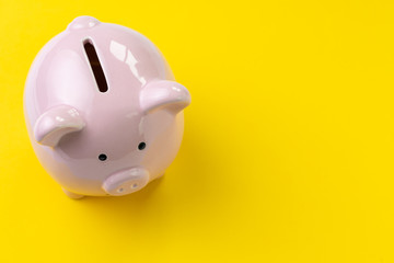 Top view of pink piggy bank on vivid yellow background with copy space, banking, budget, expense and saving concept