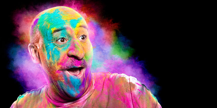 Bald smiling man with colorful face having fun. Holi color festival