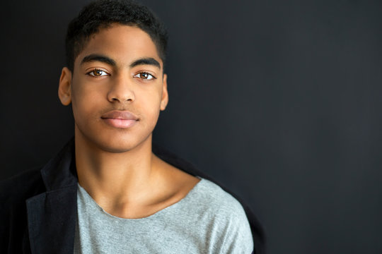 Fashion portrait of a beautiful boy on a black background. Portrait of a young African American man. Attractive teenager. 