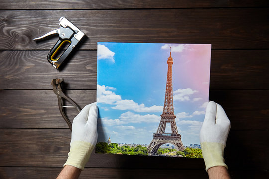 Photography printed on canvas in male hands. Image of Eiffel Tower (Paris, France)