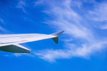 Wing of airplane flying above the clouds in the sky