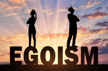 Selfish and narcissistic man and woman standing on the word selfishness turned away from each other