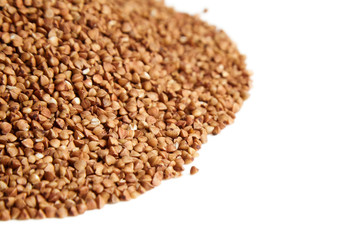 Heap of buckwheat grains. Dry brown kernel on white background. Selective focus