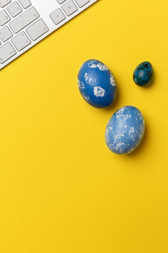Blue Easter eggs with keyboard on yellow background