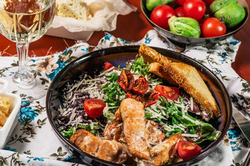 Caesar salad with salmon. Served with white wine. Salad with red fish fillet, cesar sauce, croutons, lettuce, cherry tomato, close up.