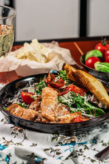 Caesar Salad with Grilled Salmon on Elegant Restaurant Plate. Served with white wine. Salat with Red Fish Fillet, Crackers, Cherry Tomatoes, Lettuce Leaves, Caesar Sauce and Parmesan Cheese