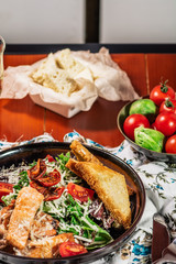 Caesar Salad with Grilled Salmon on Elegant Restaurant Plate. Served with white wine. Salat with Red Fish Fillet, Crackers, Cherry Tomatoes, Lettuce Leaves, Caesar Sauce and Parmesan Cheese
