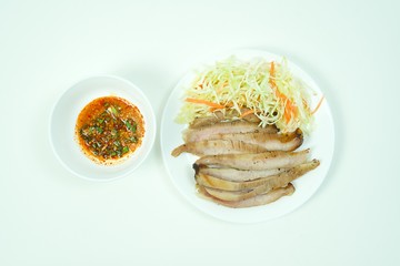 Slices of grilled pork in white plate with spicy fish sauce. Isolated white background.
