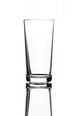 A single empty highball glass isolated on a white background with reflection. High contrast black and white, black line lighting.