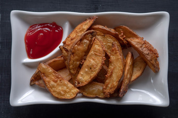 A plate with fried golden potatoes in country style with tomato sauce