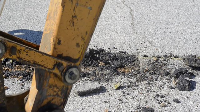 Mini excavator with narrow bucket removes the paving asphalt