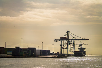 Fototapeta na wymiar Cargo ship and cranes in the dockyard of Barcelona at dusk , Spain