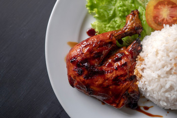 Grilled chicken leg with rice on a plate