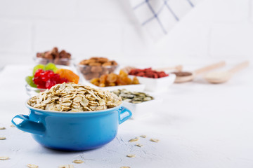 Oat flakes in blue bowl and various delicious ingredients for healthy breakfast on the kitchen table. Healthy breakfast concept.