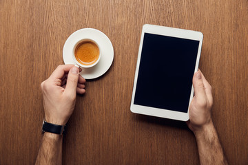 Fototapeta na wymiar cropped view of man holding digital tablet with blank screen and cup of coffee