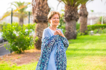 Portrait of old senior caucasian woman in outdoor with green nature and park in background and...