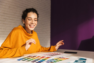 Cheerful artistic woman choosing paint color on a palette
