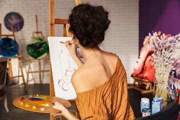 Creative beautiful woman painting at home