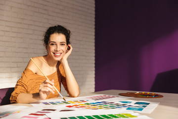 Cheerful artistic woman choosing paint color on a palette