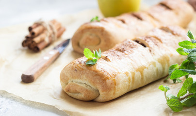 Traditional apple strudel with raisin and cinnamon on grey concrete background. Copy space.