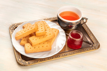 Scottish shortbread butter cookies on a vintage tray with a cup of tea, jam, and a place for text