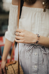 Obraz na płótnie Canvas Fashionable young blogger girl holding a circle straw bag, wearing a handmade bracelet. Concept of blogging and street style fashion. Summer and spring outfit ideas.