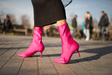 A close up shot of a young fashionable woman walking in the hot pink sock boots. Cocnept of fashion, foortwear and street style. Spring and autumn outfit ideas.