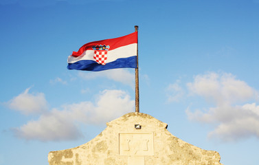 Croatia flag waving on the blue sky on the town Nin Gate.