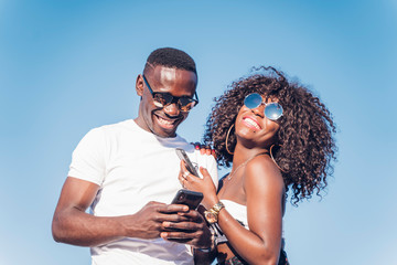 Nice couple of African man and woman with sunglasses and mobile phone.