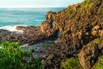 view of a rocky cliff in the ocean during sunset