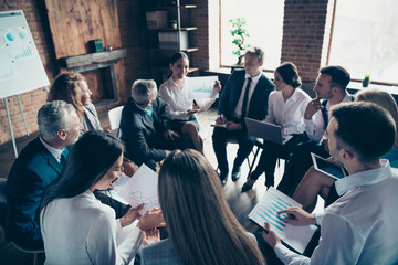Fototapeta premium Nice stylish cheerful experts professional ceo boss chief sitting on chairs in circle showing financial plan result corporate conference at modern industrial loft interior room work place space