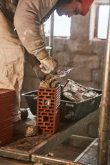 Real construction worker making a wall inside the new house.