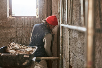 Real construction worker making a wall inside the new house.