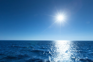  blue sky over calm sea with sunlight reflection